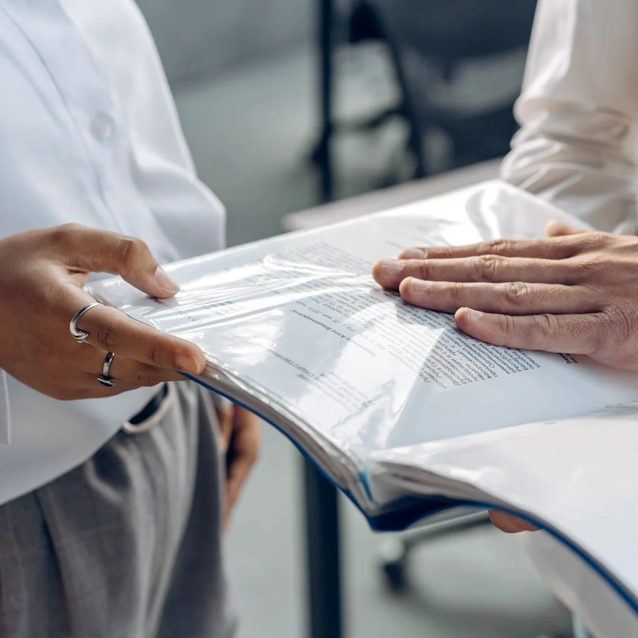 One person handing a document file to another.