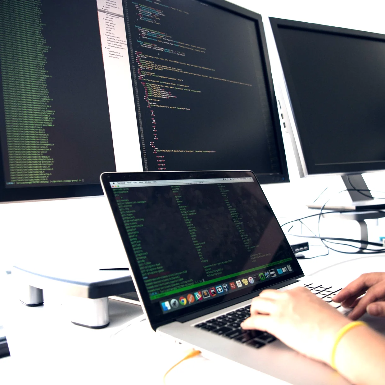 Program code on monitors at a development desk.